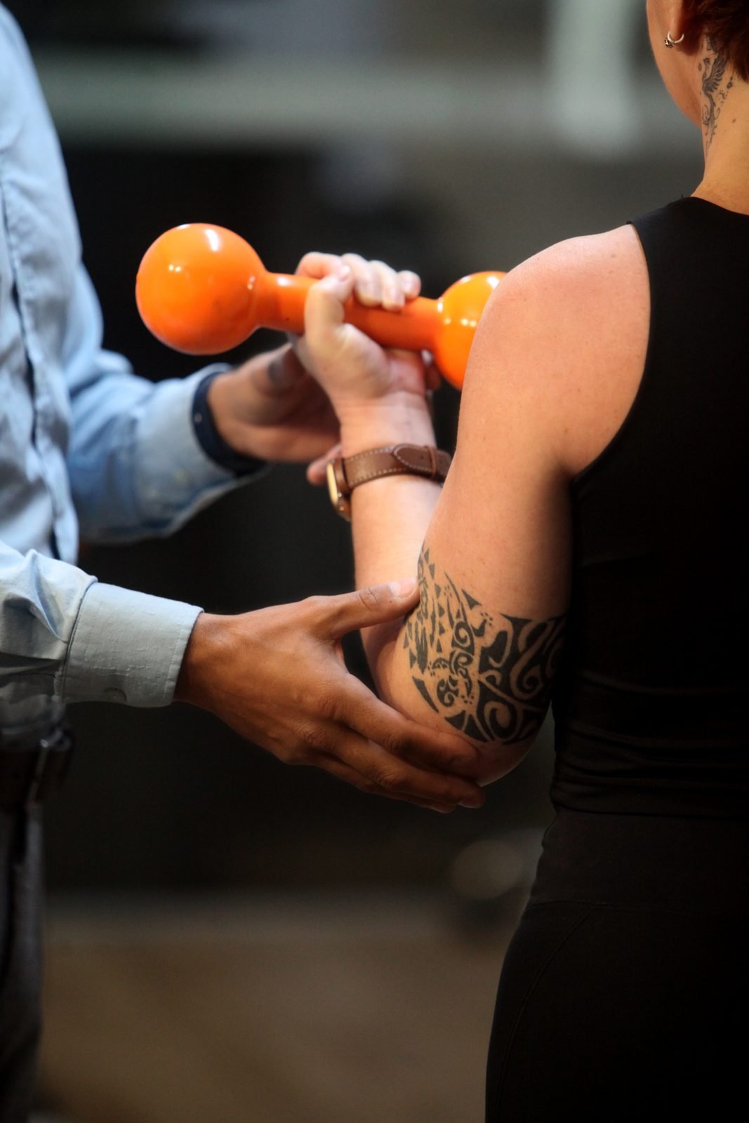 Exercício assistido com halter na reabilitação: o profissional apoia o braço do paciente